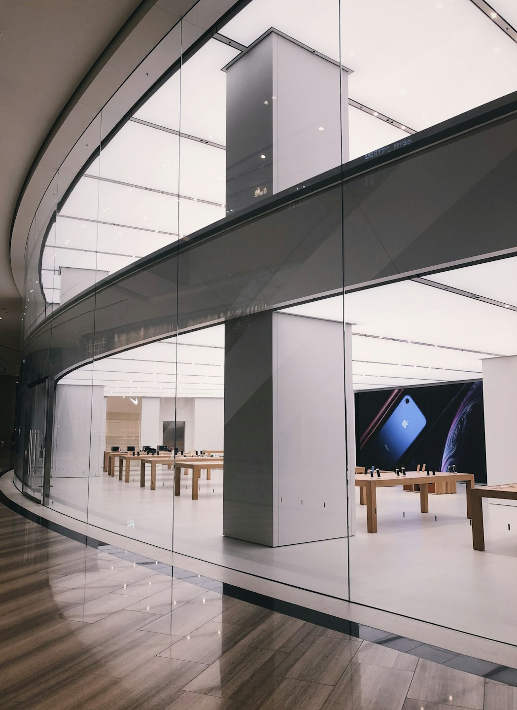 Contact Electronic devices displayed on wooden tables inside a modern store.